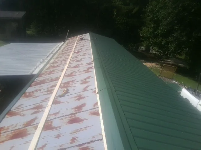 Old rusted panels beside newly installed green metal roofing — Wind Damage Roof Repair by Roofing Brothers in Short Hills
