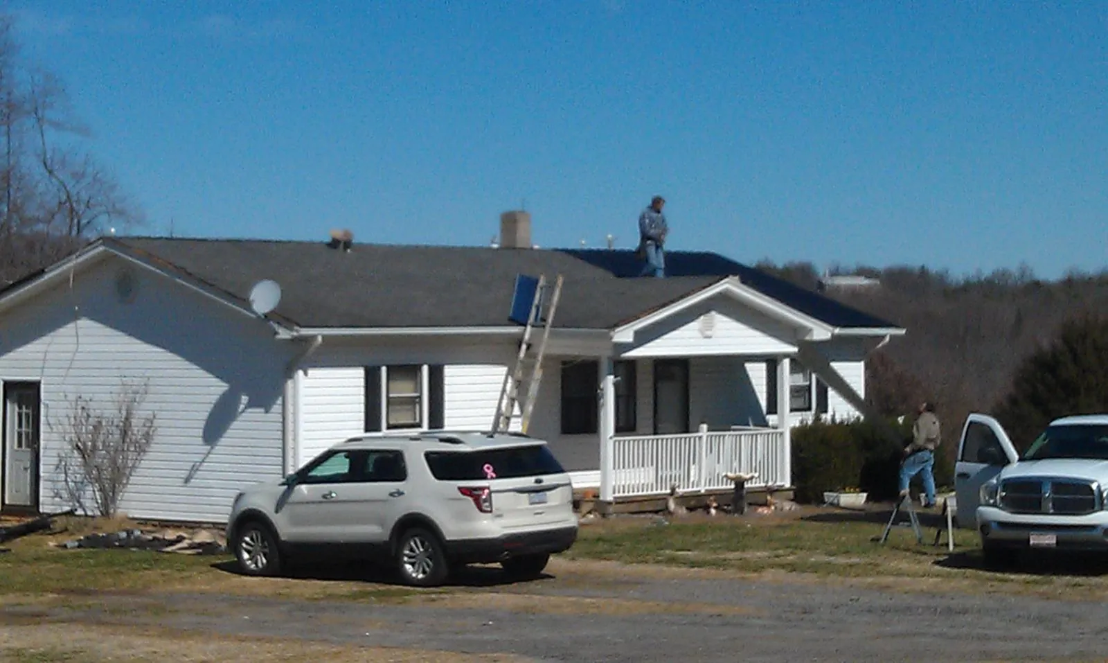 Roofers stripping shingles from a white ranch house roof in Short Hills