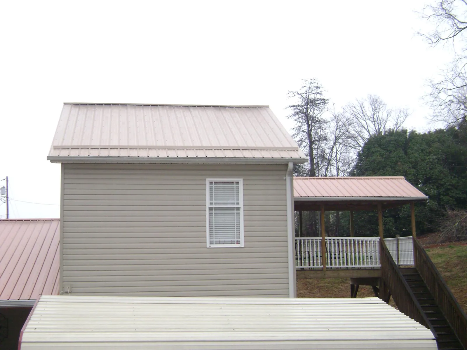 Tan metal roofs on a two story addition and attached porch, from a Roof Replacement job in Short Hills