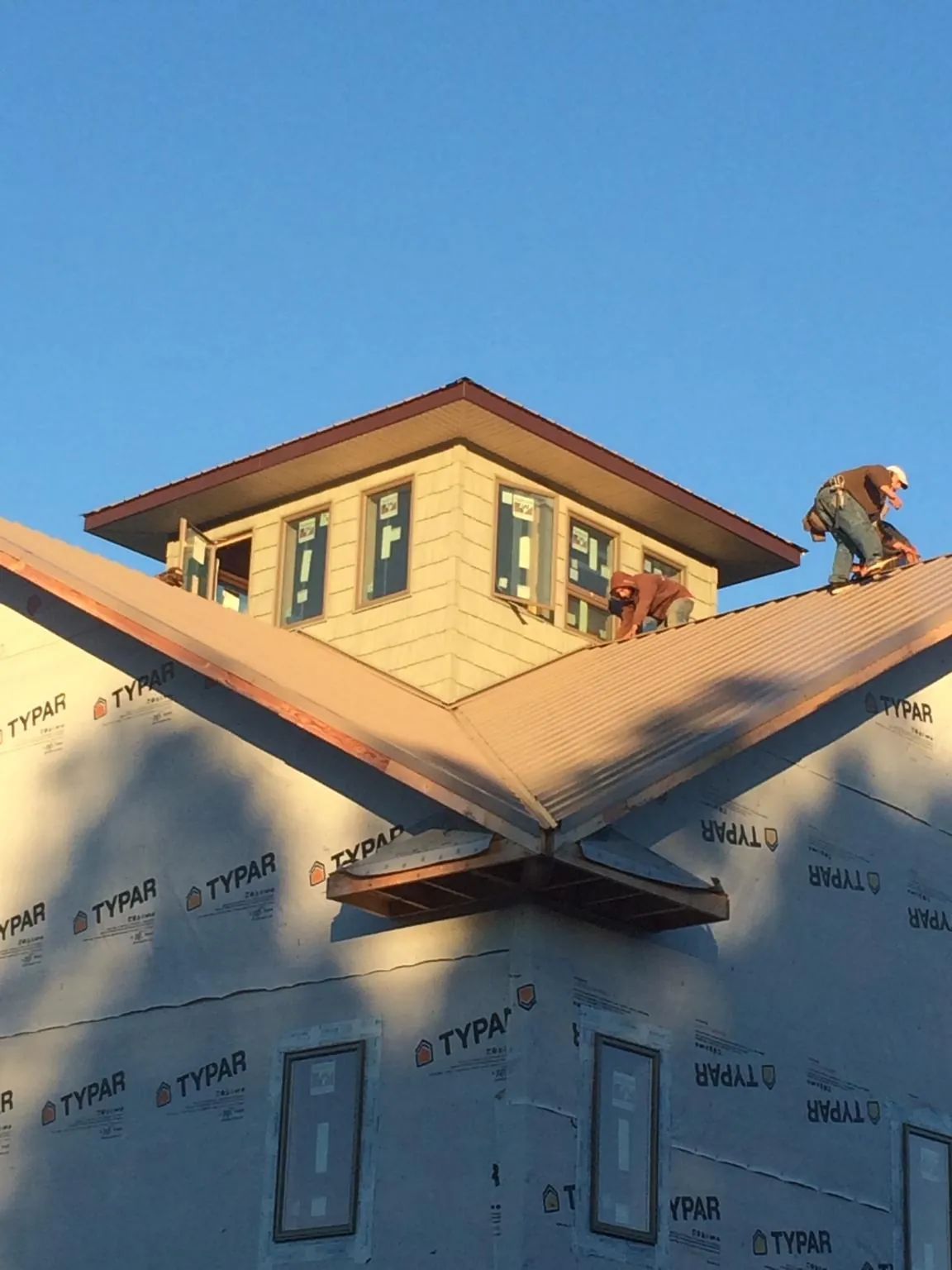 Roofers working around a rooftop cupola on a new metal roof at sunset — Roof Waterproofing in Short Hills by Roofing Brothers